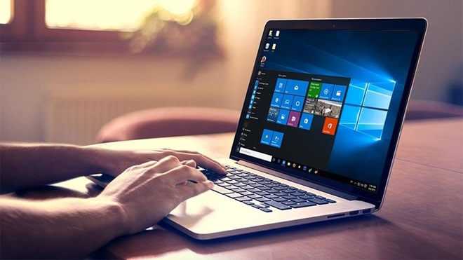 man typing on laptop with windows 10 screen